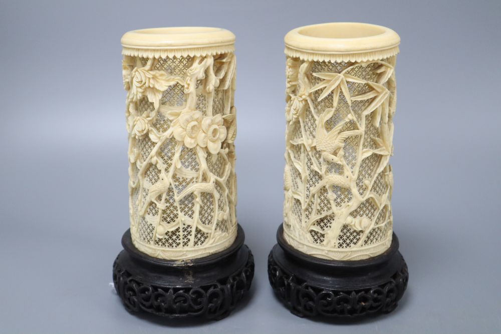 A pair of Japanese carved and pierced ivory brush pots, on hardwood stands, height 20cm